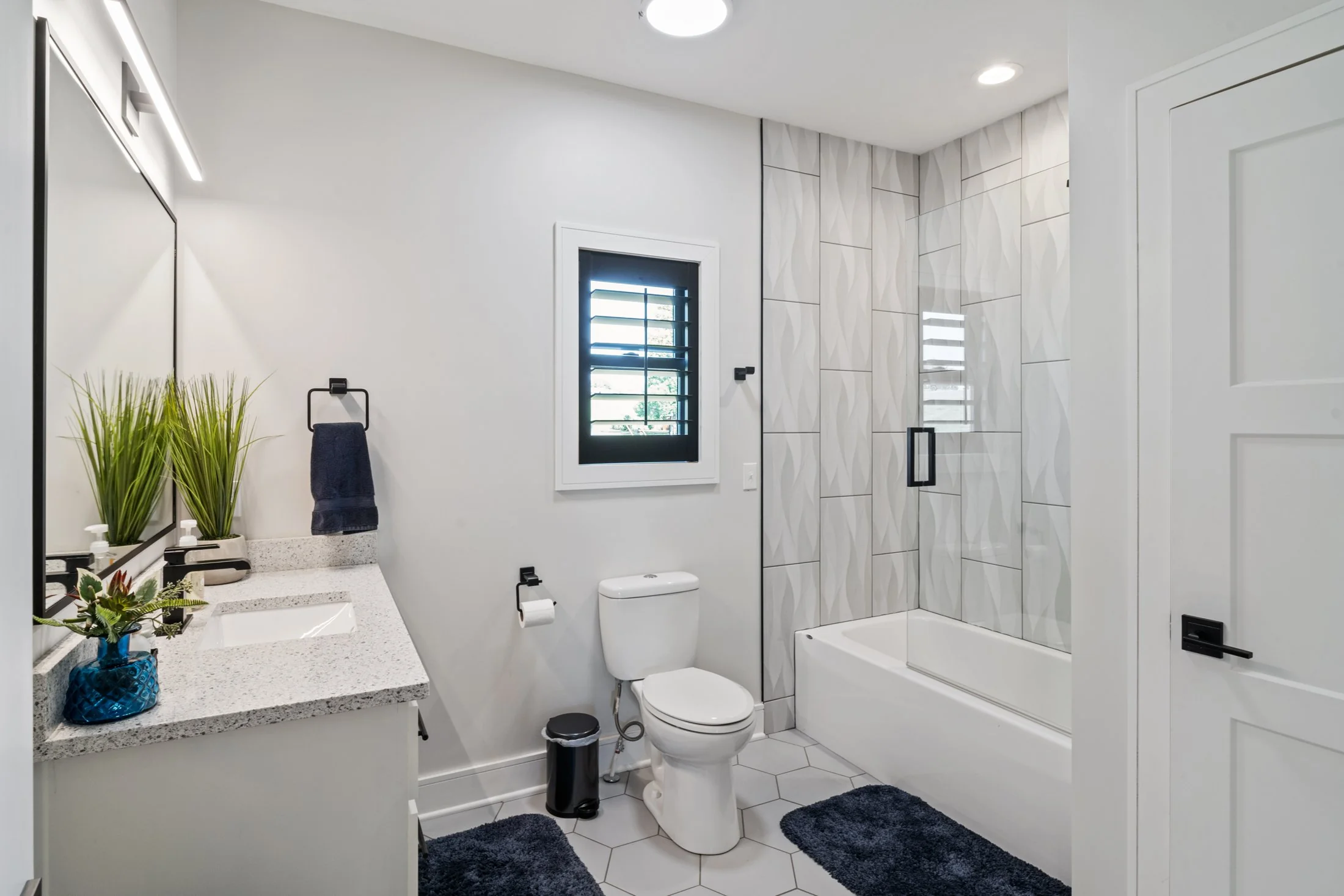 Contemporary white bathroom with geometric tile and black fixtures at 102 Angler Point.