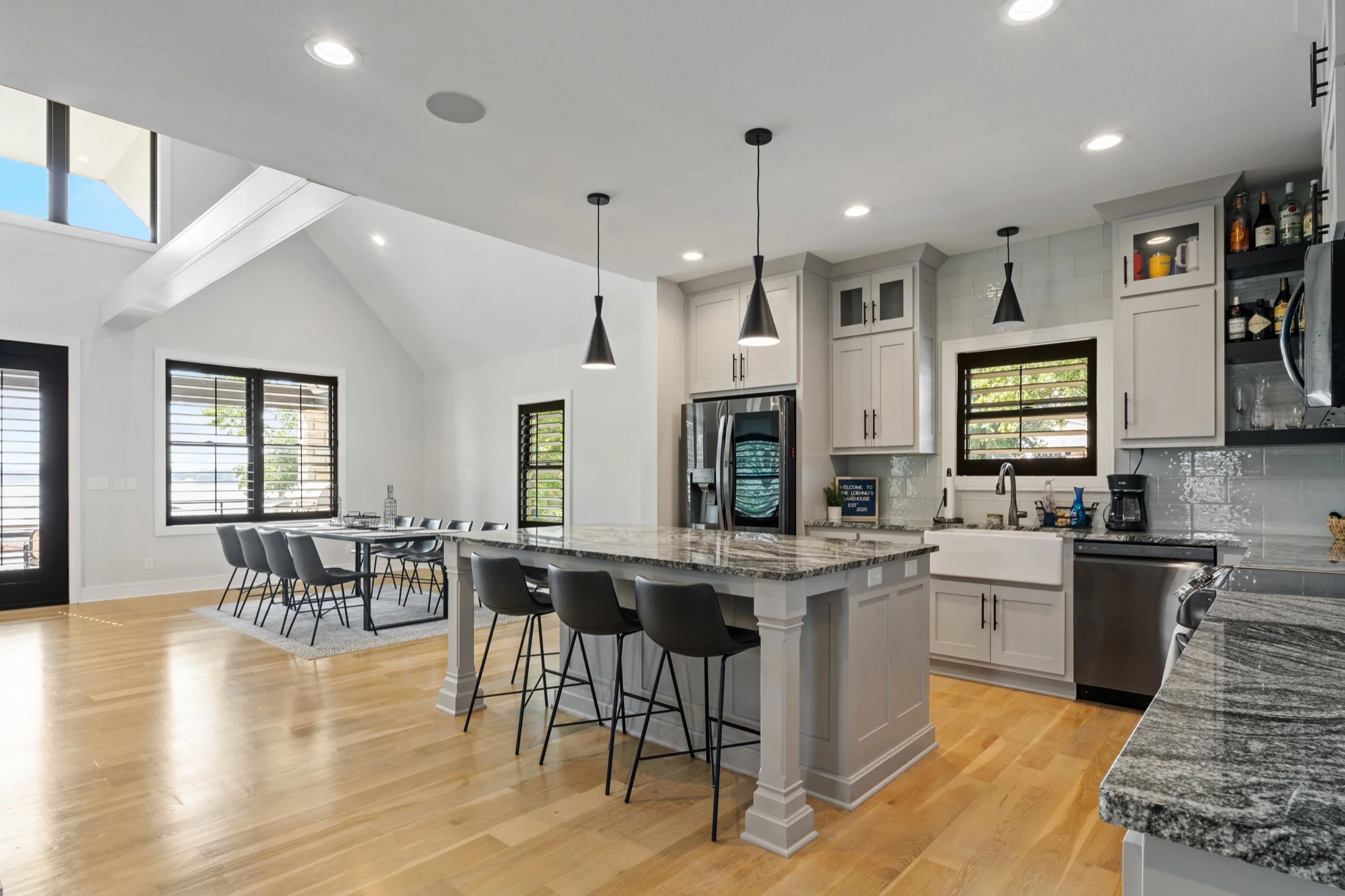 White kitchen with black pendant lights and a large island.