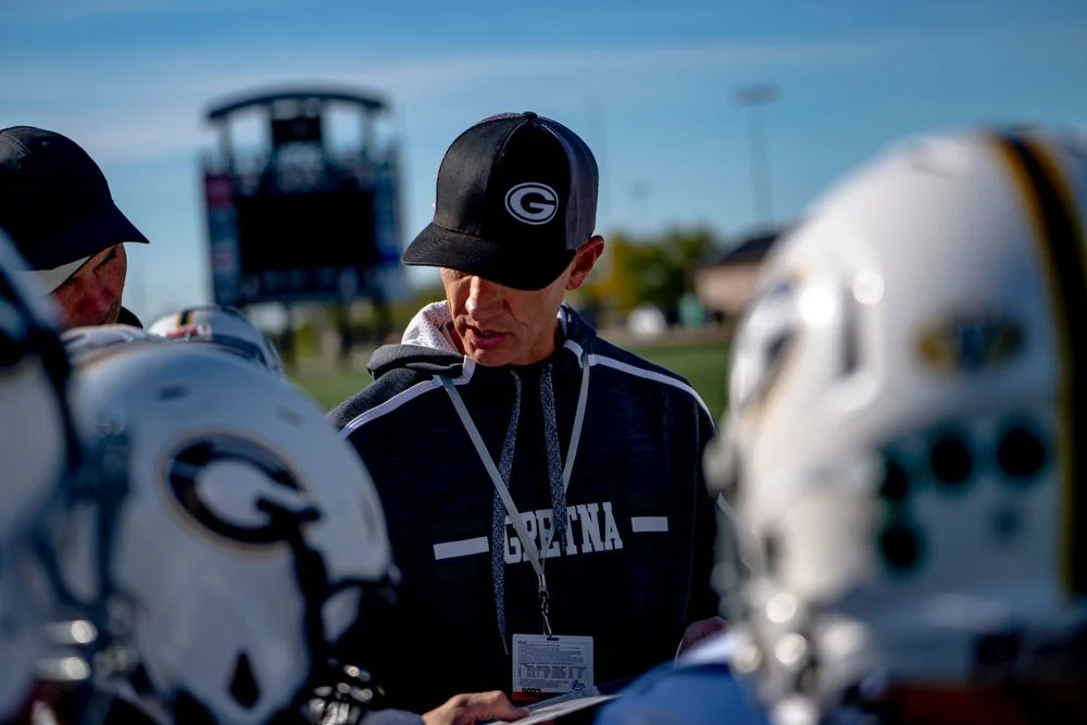 Coach speaking among football players wearing helmets.
