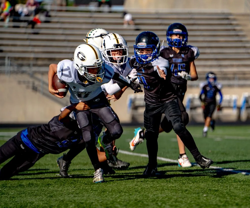 Football ball carrier and defenders during a tackle.
