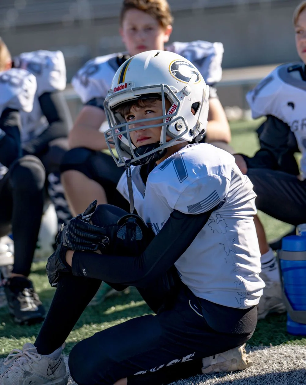 Football player seated on the sideline.